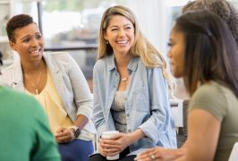 Mid adult woman talks about something during a support group or group therapy meeting.