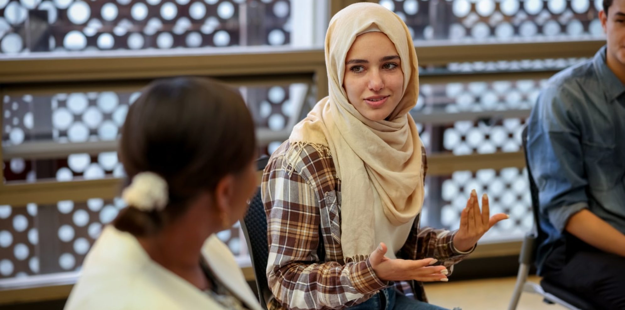 Muslim college students talking to a group in a counseling session - mental health concepts