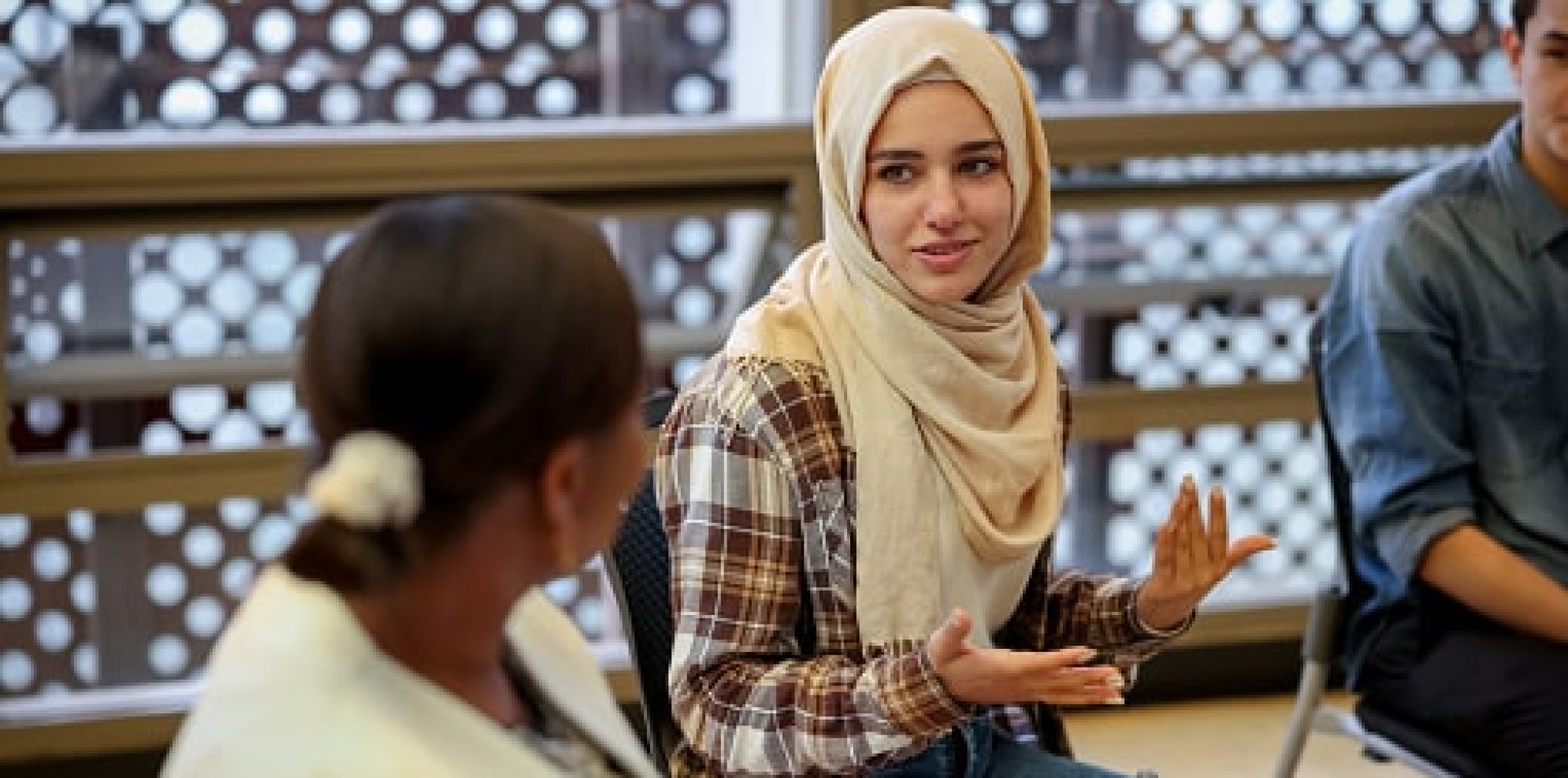 Muslim college students talking to a group in a counseling session - mental health concepts